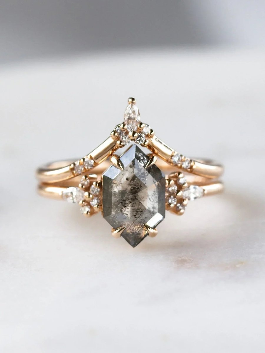 Gold ring with a large diamond and smaller diamonds on a marble surface