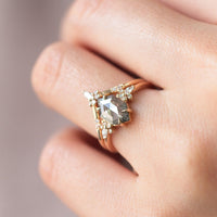 Minimalistic and art deco styled hexagon salt and pepper diamond engagement ring in 14k rose gold with a marquise and round diamonds arranged on each side on model's hand.
