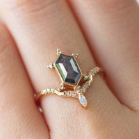 Unique art deco styled hexagon salt and pepper diamond engagement ring in 14k rose gold with a marquise and round diamonds on model's hand.