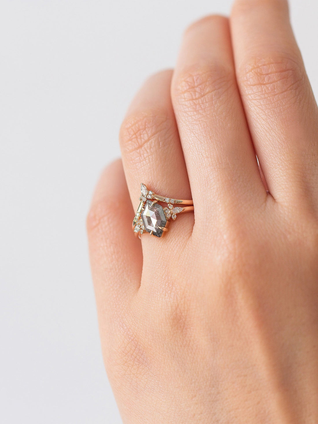 Minimalistic and art deco styled hexagon salt and pepper diamond engagement ring in 14k rose gold with a marquise and round diamonds arranged on each side on model&