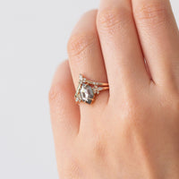 Minimalistic and art deco styled hexagon salt and pepper diamond engagement ring in 14k rose gold with a marquise and round diamonds arranged on each side on model's hand.