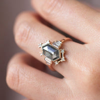 Minimalistic and art deco styled hexagon salt and pepper diamond engagement ring in 14k rose gold with princess and baguette diamonds on model's hand.