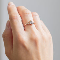 Unique art deco styled hexagon shaped salt and pepper diamond engagement ring in 14k rose gold with smaller marquise, round, and princess cut diamonds on model's hand.