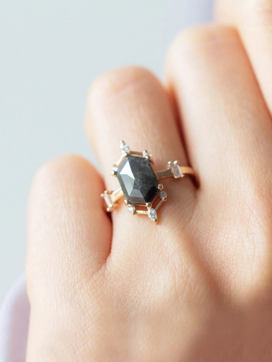 hand wearing a contemporary Art Deco ring with hexagon center stone, semi-halo detail