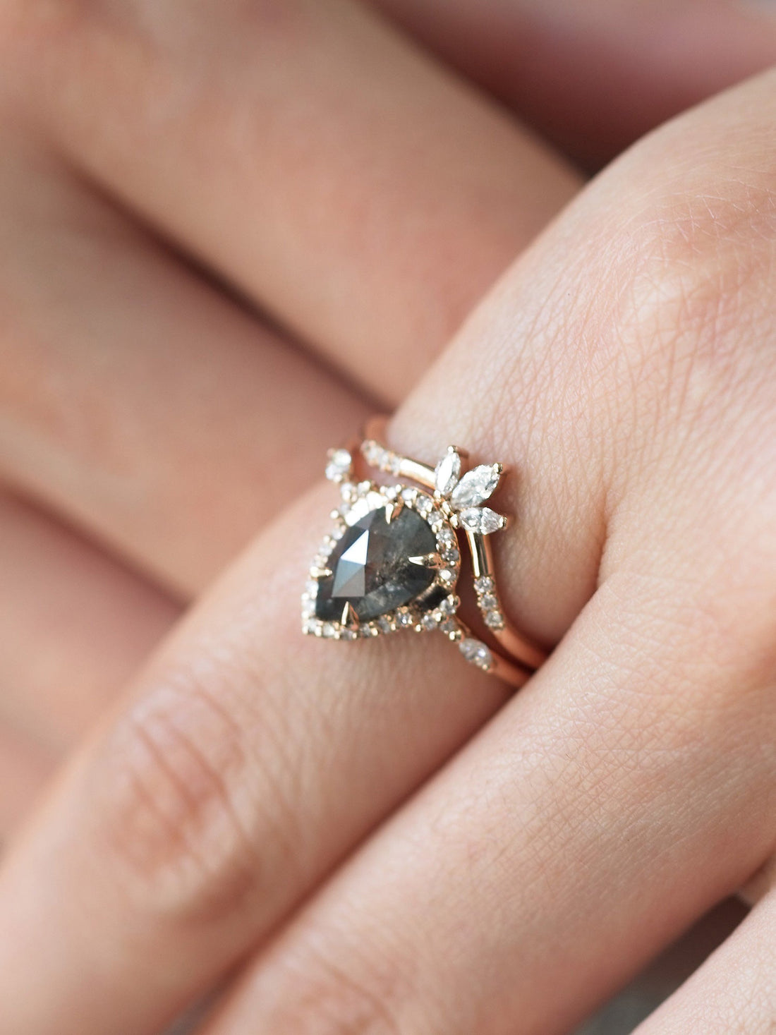 Pear-shaped salt and pepper diamond engagement ring in 14k rose gold  with matching band inspired by the art deco style and minimalism on model&