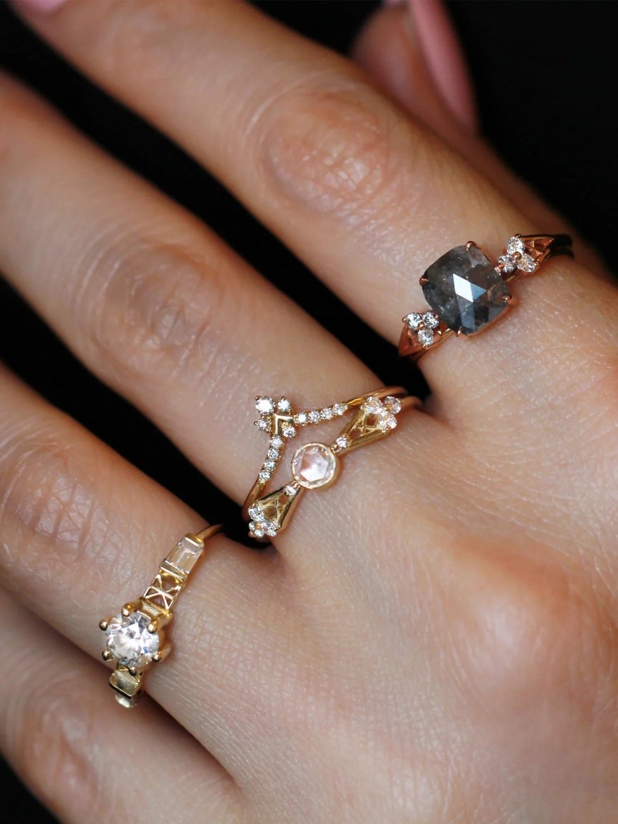 Hand dramatically lit wearing several Art Deco rings, with petite yellow gold ring stacked under chevron band at the center