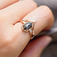 Unique art deco styled hexagon salt and pepper diamond engagement ring in 14k rose gold with baguette and round diamonds on model's hand.