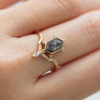 Unique art deco styled hexagon salt and pepper diamond engagement ring in 14k rose gold with a marquise and round diamonds on model's hand.