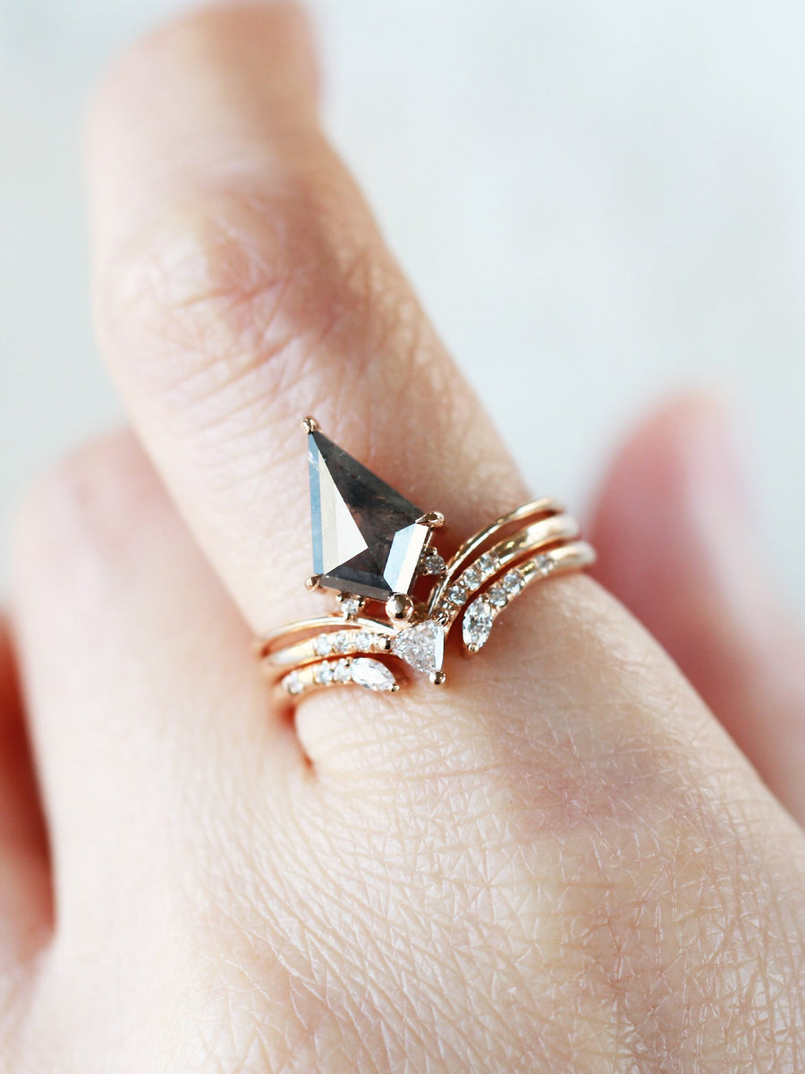 Minimalistic and art deco styled kite salt and pepper diamond engagement ring in 14k rose gold with a trilliant and round diamonds on model's hand.