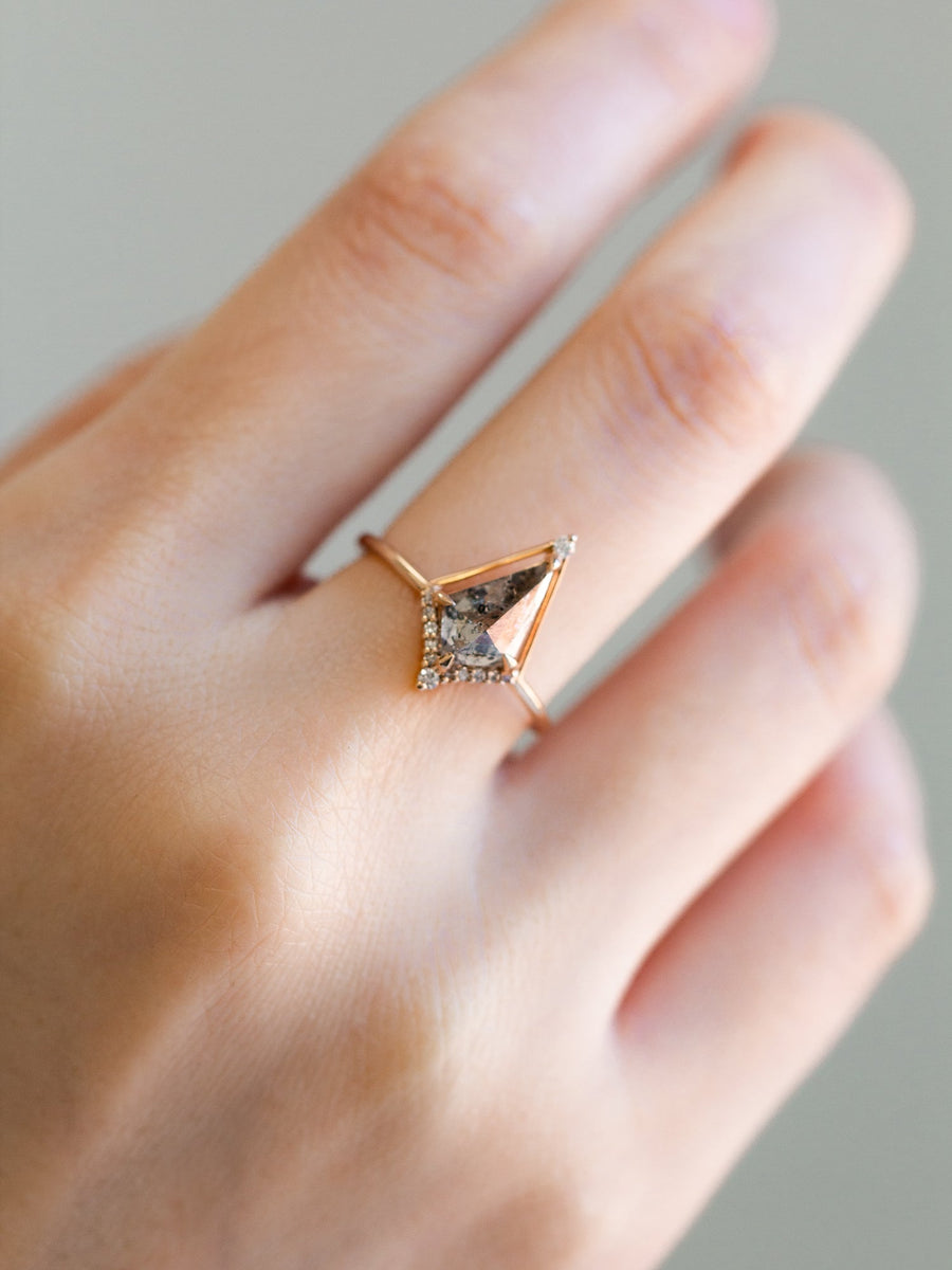 Kite shape salt and pepper diamond engagement ring with smaller round diamonds in 14k gold inspired by the art deco style and minimalism on model’s hand.