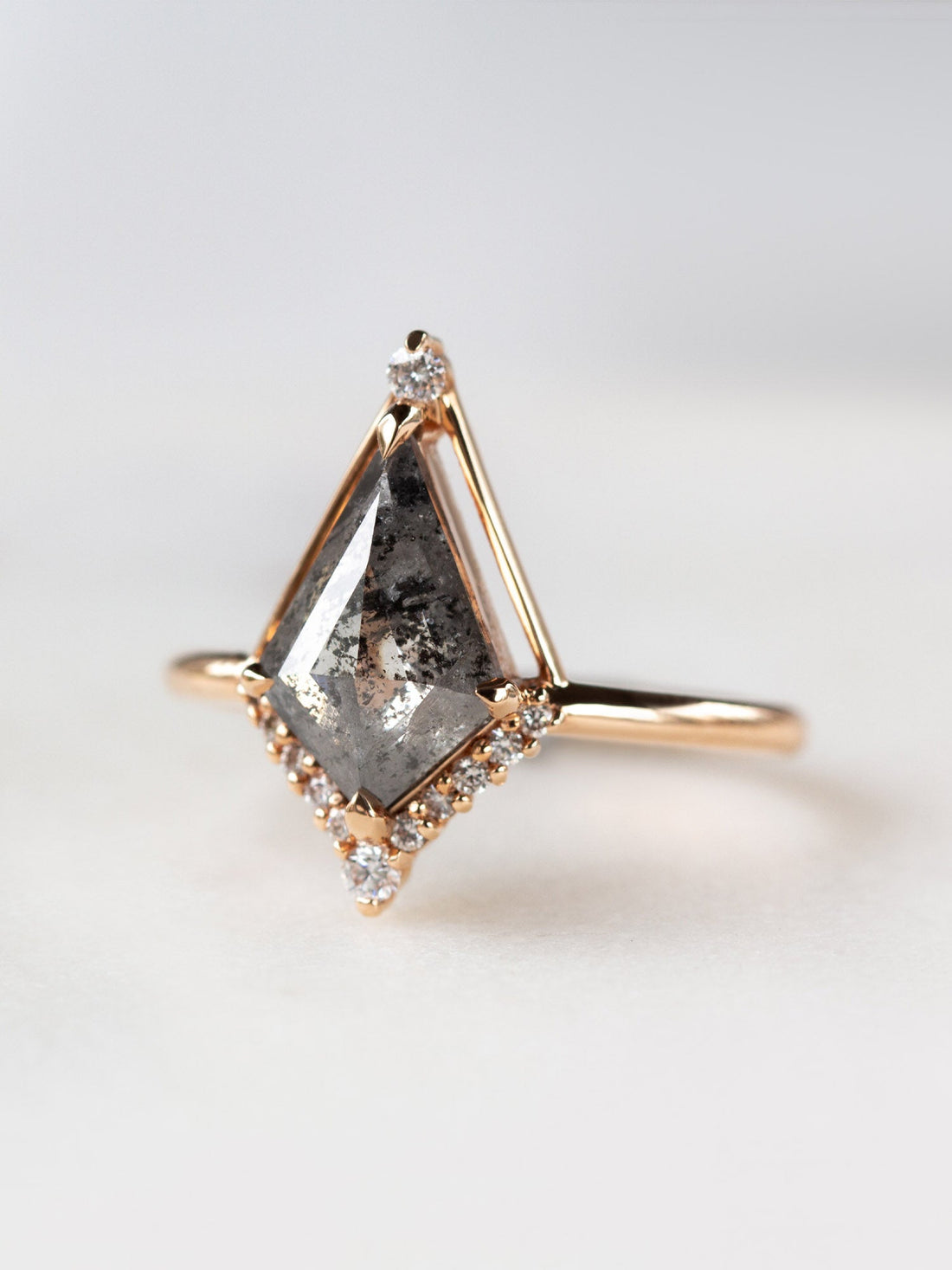 Kite shape salt and pepper diamond engagement ring with smaller round diamonds in 14k gold inspired by the art deco style and minimalism.