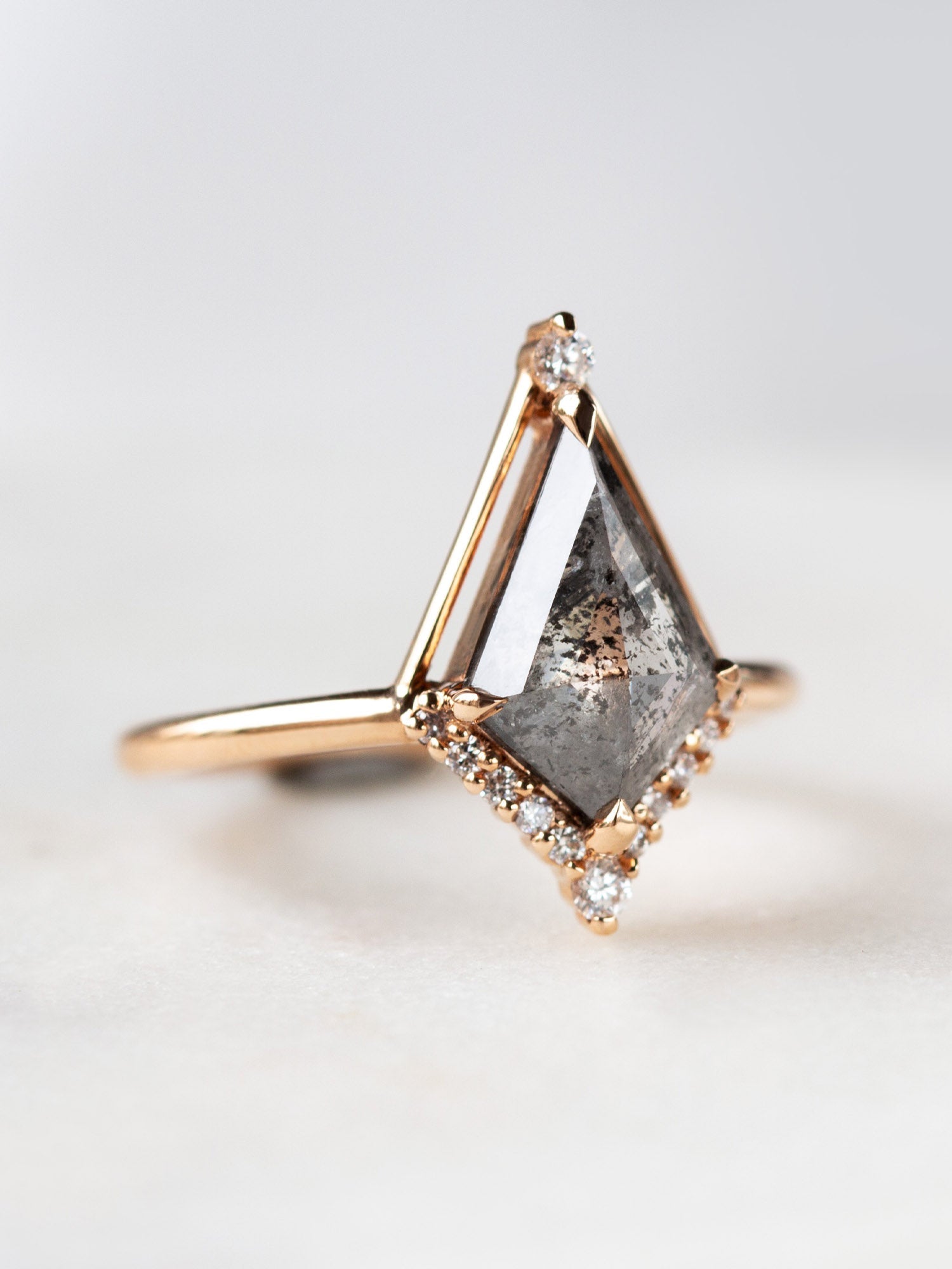 Kite shape salt and pepper diamond engagement ring with smaller round diamonds in 14k gold inspired by the art deco style and minimalism.