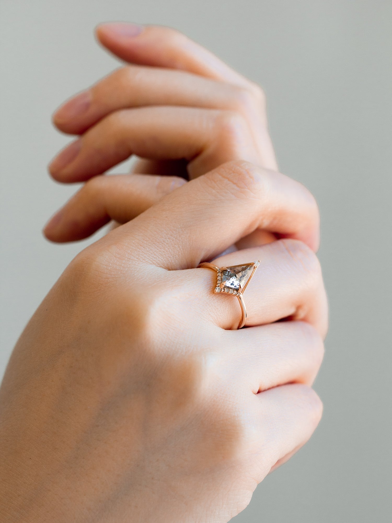 Kite shape salt and pepper diamond engagement ring with smaller round diamonds in 14k gold inspired by the art deco style and minimalism on model’s hand.