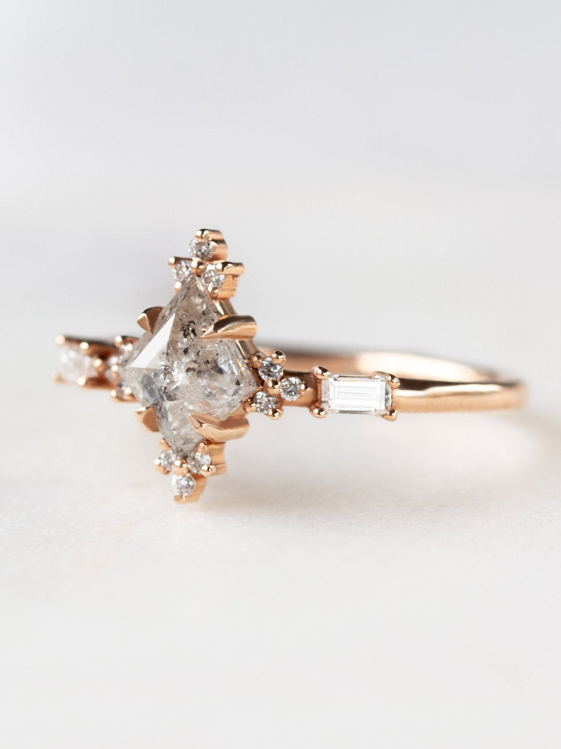 Art deco style minimal kite shape salt and pepper diamond engagement ring in 14k rose gold with smaller baguette and round diamonds.