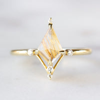 Kite shape rutilated quartz engagement ring with smaller round diamonds in 14k gold inspired by the art deco style and minimalism.