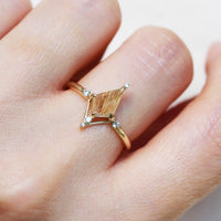 Kite shape rutilated quartz engagement ring with smaller round diamonds in 14k gold inspired by the art deco style and minimalism on model's hand.