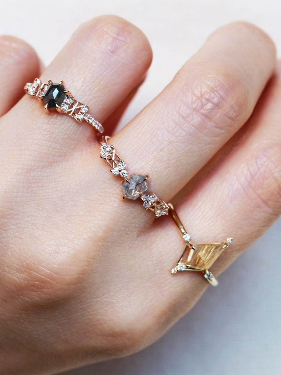 Kite shape rutilated quartz engagement ring with smaller round diamonds in 14k gold inspired by the art deco style and minimalism on model's hand.